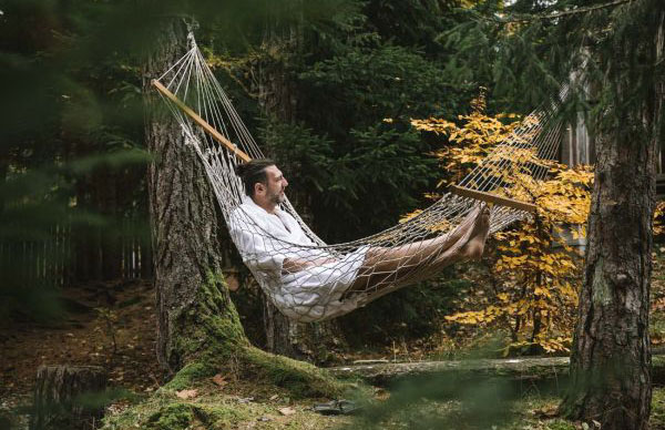 Ein Mann liegt im Wald in einer Hängematte