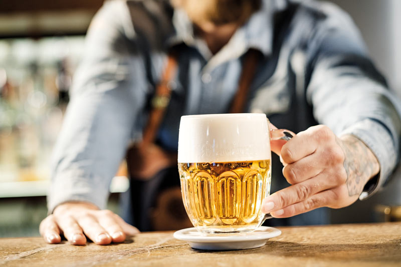 Ein Barkeeper hält ein Glas Bier in der Hand