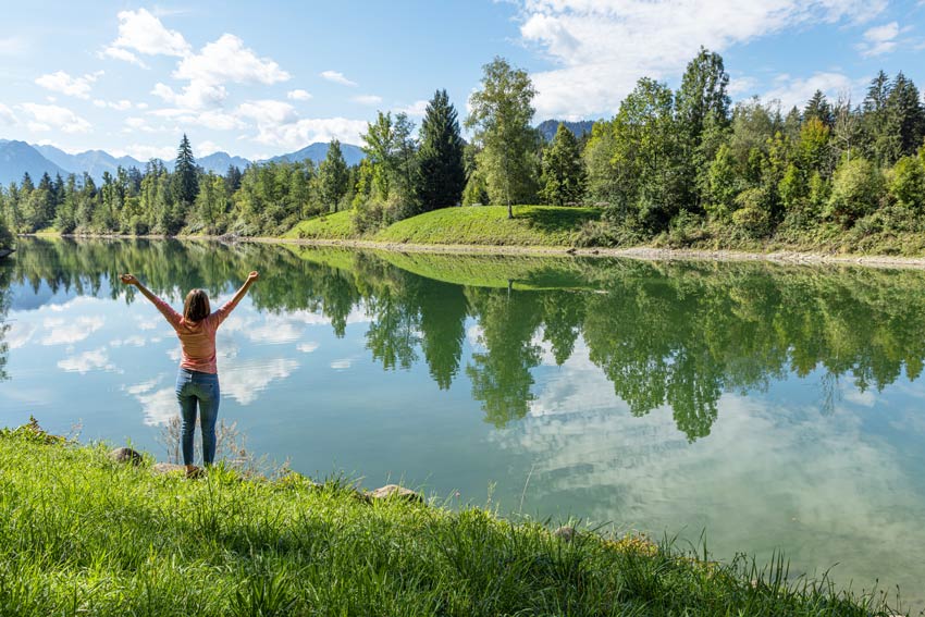 Eine Frau streckt die Arme in die Luft am Auwaldsee in Fischen