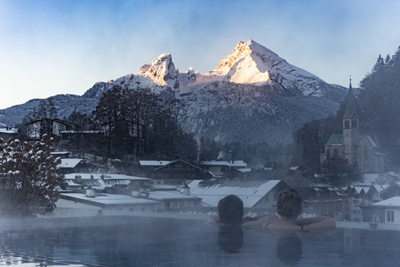 Zwei G&auml;ste sitzen im Pool und blicken auf den Watzmann